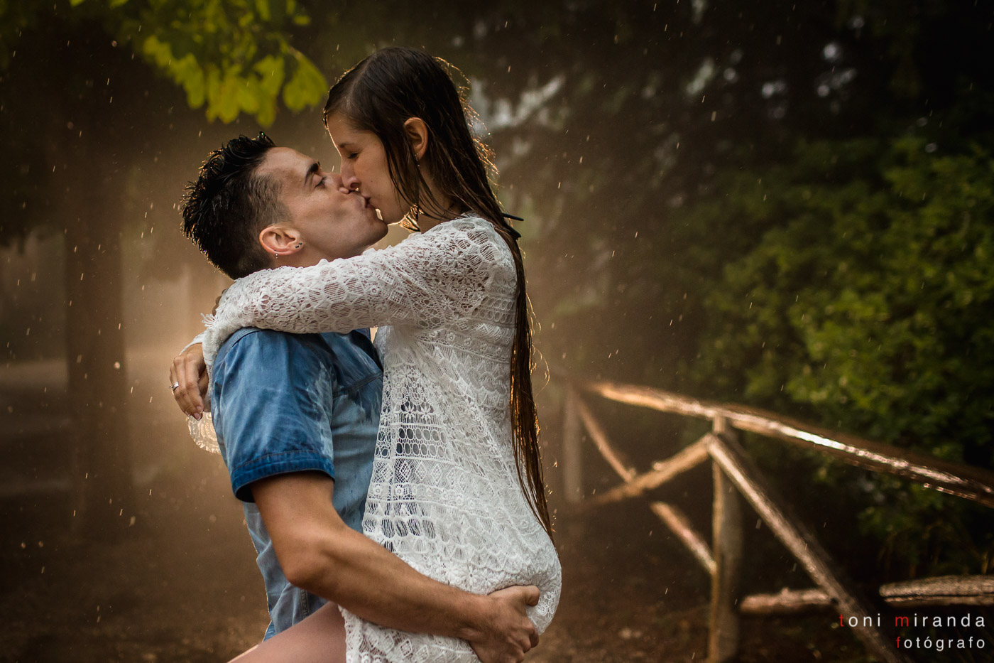 novios besandose bajo la lluvia en el campo